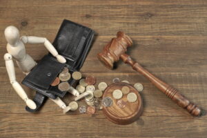Wood Humane Figurine, Empty Black leather Male Wallet, Different British Coins And Judges Gavel on Rough Brown Wood Table Background, Top View, Copy Space